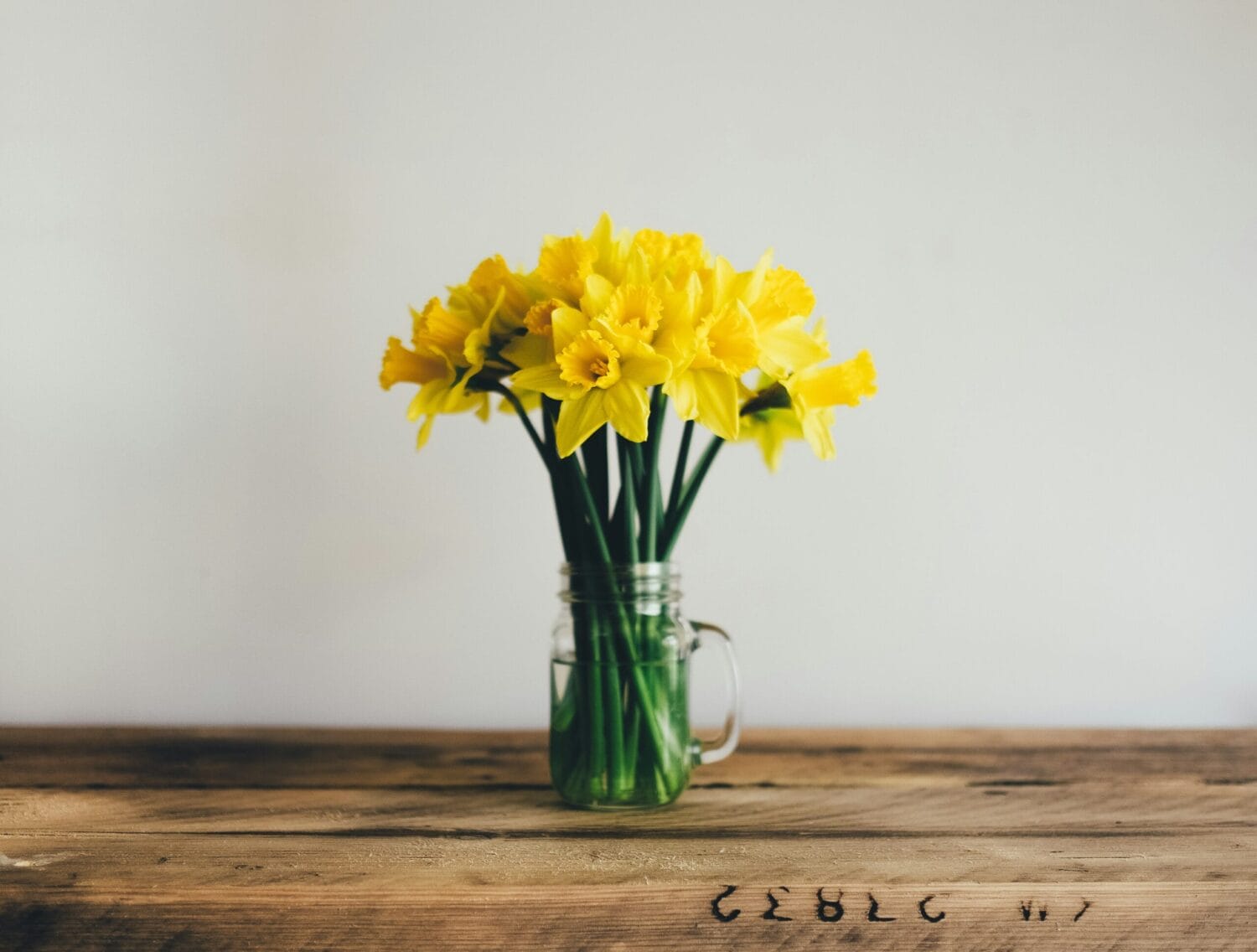 A bouquet of daffodils sits in a butcher block table.